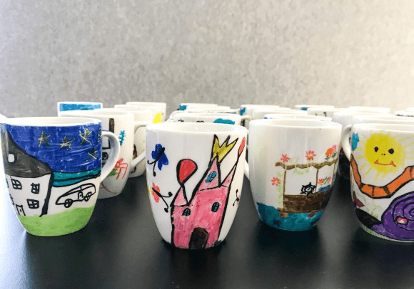 „Traumhaus-Tassen“, die von Kindern im Rahmen einer Kooperation kreiert worden sind.